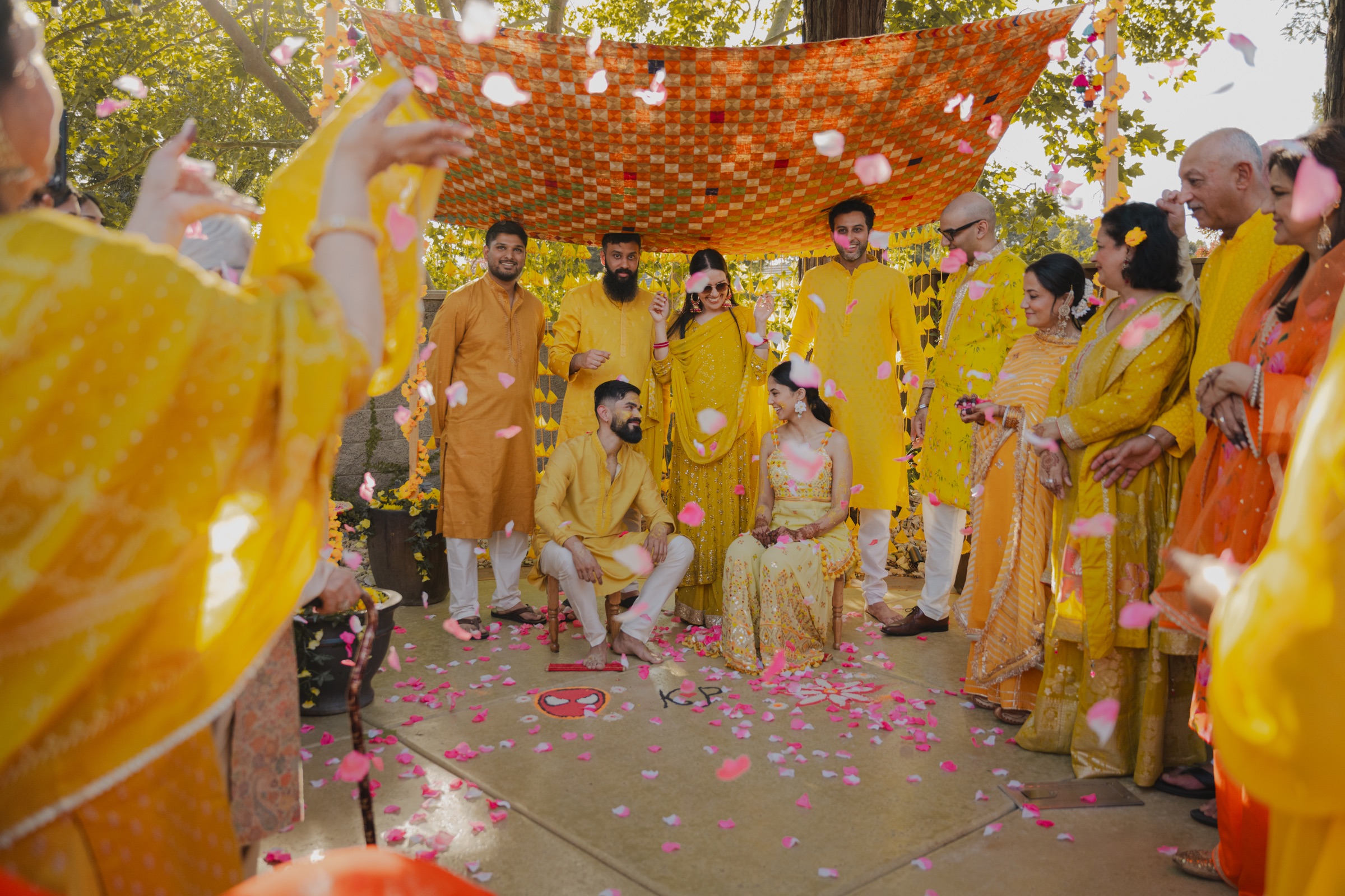 Pia and Konark surrounded by family and falling flower petals at their Haldi celebration